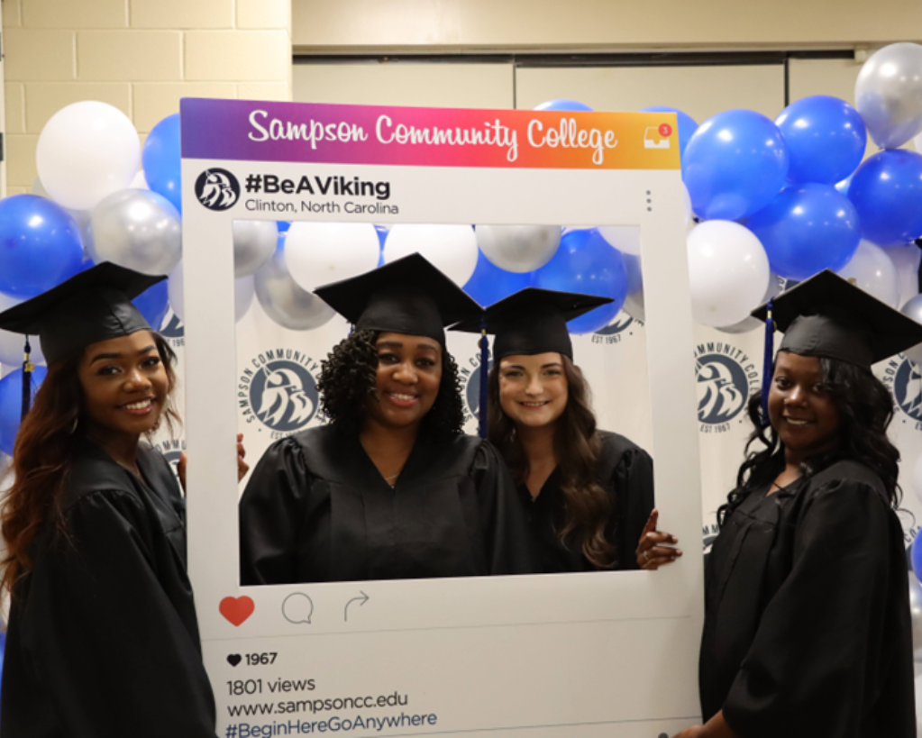 Four female students smiling at graduation photo booth