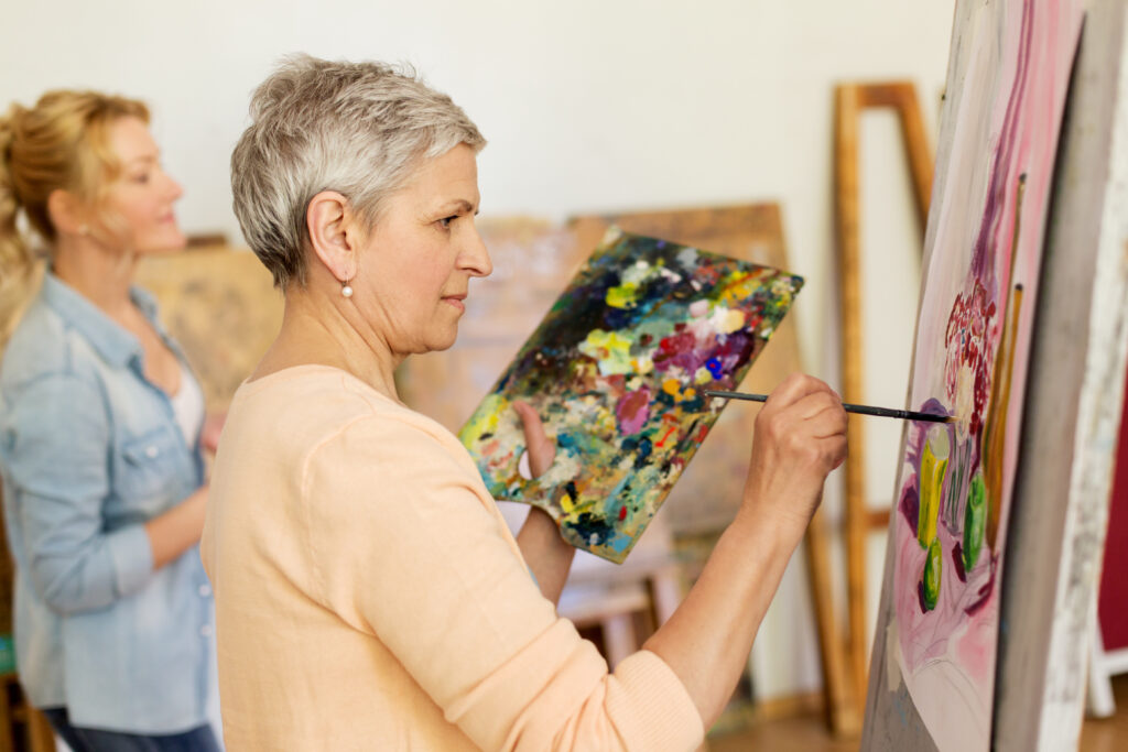 Senior woman painting at art school studio